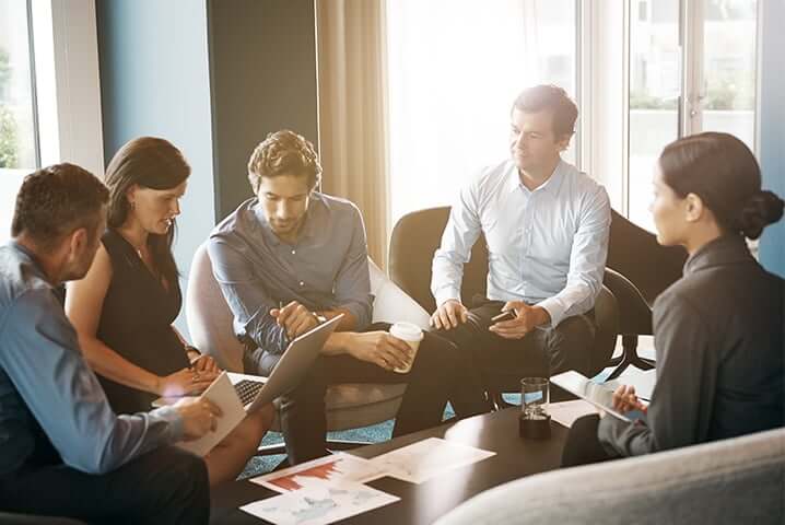 older executive and a group of young employees sitting around a coffee table