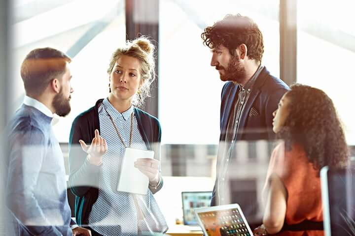 4 employees having a discussion in an office