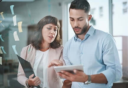 male and female employee looking at a notebook in an office