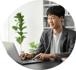 A person in a suit smiling while using a laptop.