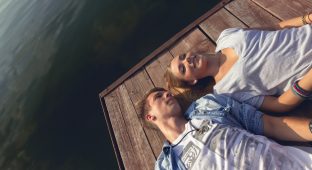 Young Couple Relaxing Near River Enjoying Sunny Day