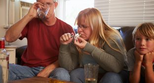 Parents Sit On Sofa With Children Taking Drugs And Drinking