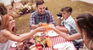 Happy young family having lunch barbecue in the garden on a sunny day.