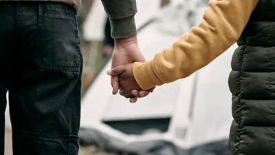 Child and adult hold hands outside of tent