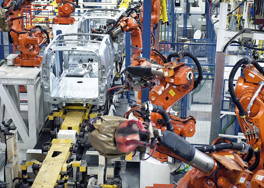 Vehicle factory manufacturing with robotic arms and automation.