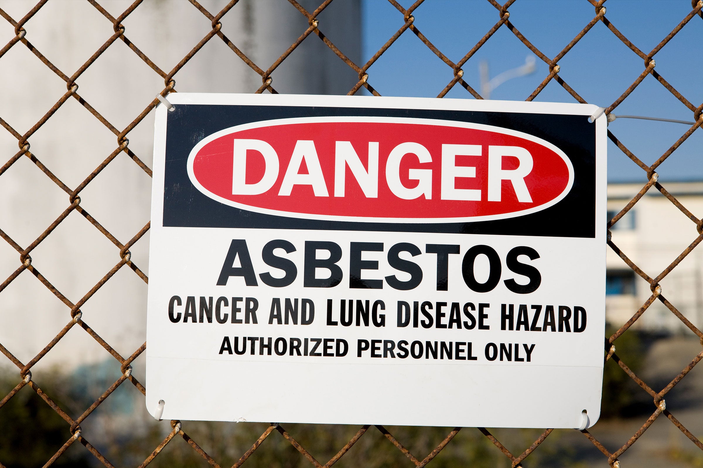 Danger sign on a chain link fence warning of asbestos