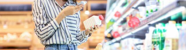 Person in supermarket checking a label on a food product