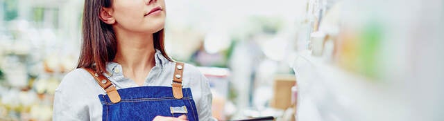 A young person holding a tablet and doing inventory in a store