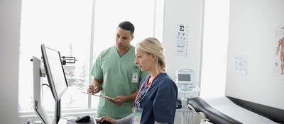 Nurses using computer in clinic examination room