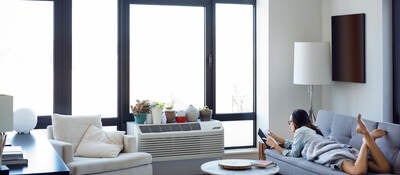 Woman reading book while lying on sofa at home