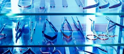 An array of medical devices sit within a cabinet basking in UV light.