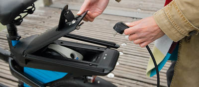 Woman charging electric bike outdoors