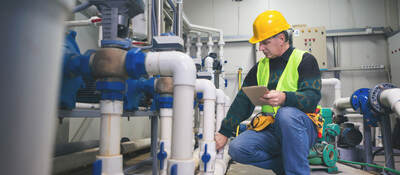 Senior repairman in boiler room checking pipes