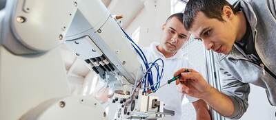 Two techs fine tuning a robotic arm