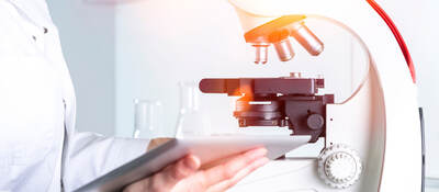 Scientist reviewing notes next to a microscope