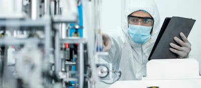 Shot of Caucasian Engineers using digital tablet for inspection quality of producing protective face mask in automated production line.