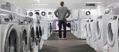 A person looking at many washers and dryers