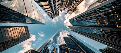 Upward view of the blue sky surrounded by towering skyscrapers