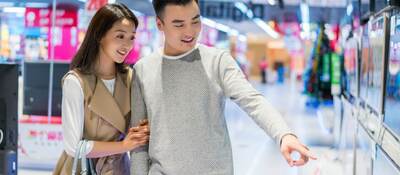 Young couple buying television in electronics store