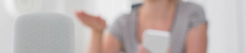 A woman uses wireless and interoperability services to operate a kitchen device with a smart phone.