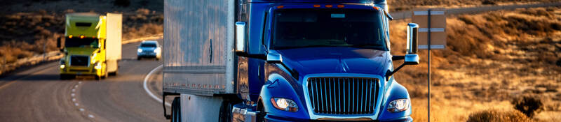 A semi truck driving down a highway at dusk