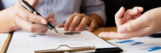 Closeup of hands writing on a clipboard at a meeting