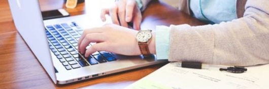 A person sustains her search for information on her laptop, comforted by her cup of hot tea.