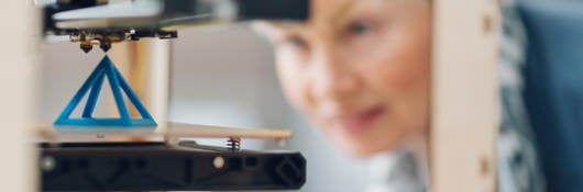 Photo of a woman working by a 3D printer