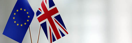 European union and British flag pair on a desk over defocused background