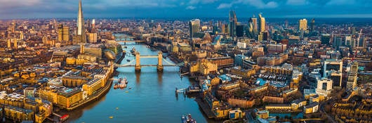 Golden hour aerial view of London’s skyline, including the Tower Bridge and famous skyscrapers.