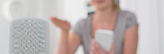 A woman uses wireless and interoperability services to operate a kitchen device with a smart phone.