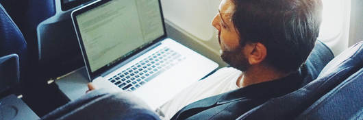 Man using a laptop on an airplane