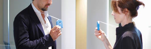 A man faces a woman with both hold an ID badge on a layard that is on their neck