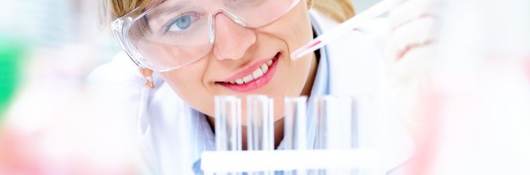 Female scientist dripping liquid into vials 