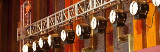 Theater lights hang from backstage scaffolding, ready for the upcoming performance. 