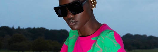 Woman wearing pink and green dress and sunglasses