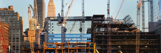 Glass office building surround by cranes