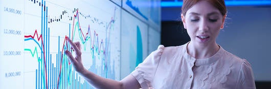 woman pointing to a chart on a whiteboard and using an ipad