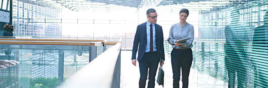 Two employees having a walking meeting in a glass building