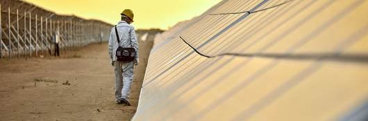 Outdoor solar pnael test facility with golden sky  and with man inspecting PV solar panels