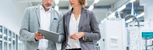 Two workers collaborating on a device while walking