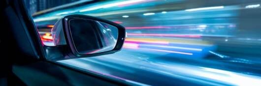 View from inside a moving car looking out of the passenger side with city lights in view