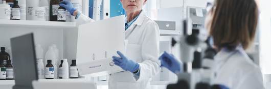 Gray-haired female scientist holding binder in lab