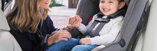 Child in car seat with a mom helping buckle in the child