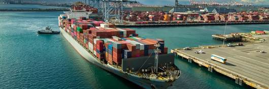 Tugboat maneuvering cargo ship at Dockside in Port of Long Beach.