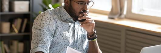 Person holding papers intensely looking at his open laptop