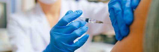 Medical worker wearing blue gloves injecting a patient in the arm