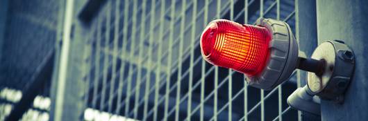 A red emergency light over a commercial building door.