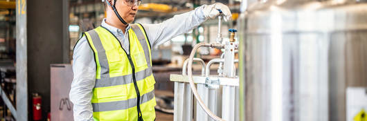 Worker operating a gas tank in a factory.  