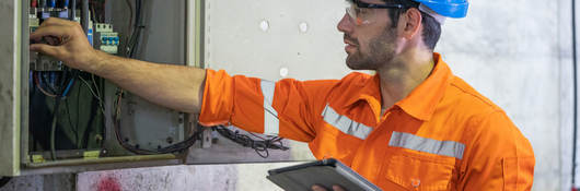 An electrician working at a circuit electrical panel.